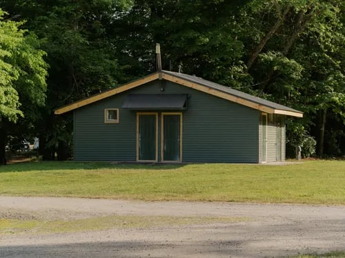 Small wooden sleeper cabin with a porch, surrounded by fall foliage