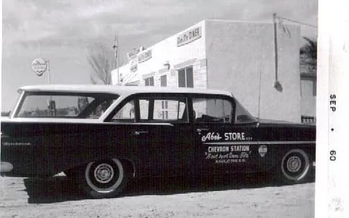 Vintage black and white photo of 'Abe's Store' building and a classic car
