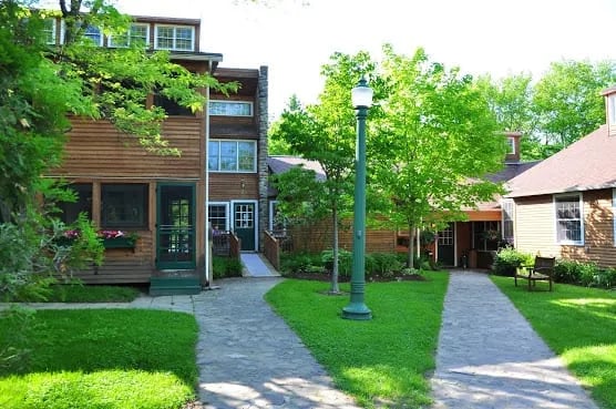 Wooden inn building with a green lamp post and paved walkways on a sunny day