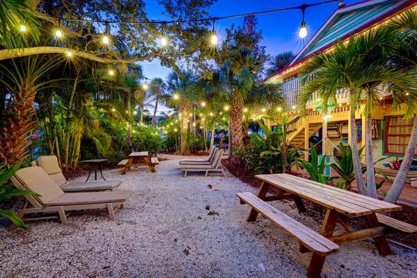 White wooden pergola over a brick pathway leading to a waterfront pool area