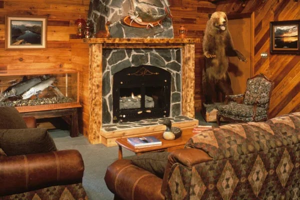 Cozy lodge common area with a stone fireplace and a standing bear taxidermy