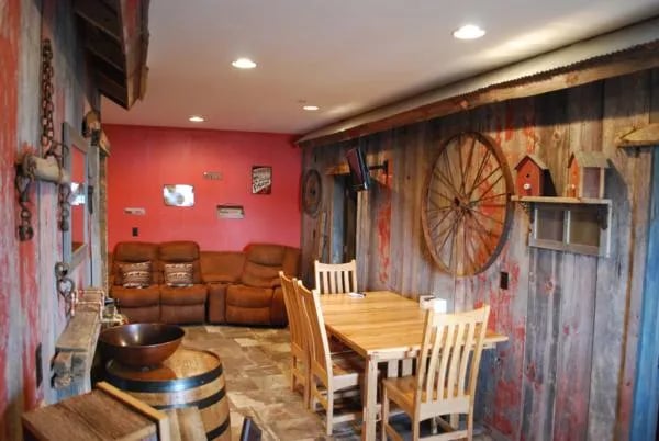 Rustic common area with a wooden dining table, leather sofa, and wagon wheel decor