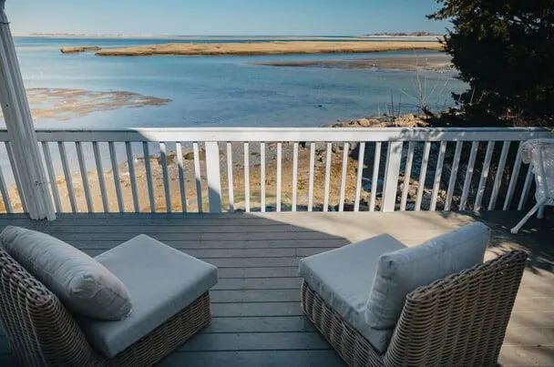 Aerial view of a waterfront house with a long dock extending into the water, surrounded by trees