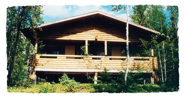 Rustic wooden cabin with a covered porch surrounded by trees
