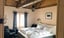 Cozy bedroom with light wood paneling, exposed wooden beams, and a double bed with white linens