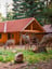 Exterior of wooden cabin with 3 deer grazing on grass out front