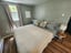 Serene bedroom with a queen bed, light green walls, and wood-look flooring