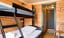 Bedroom with a black bunk bed, wooden walls, and an open doorway leading to another room