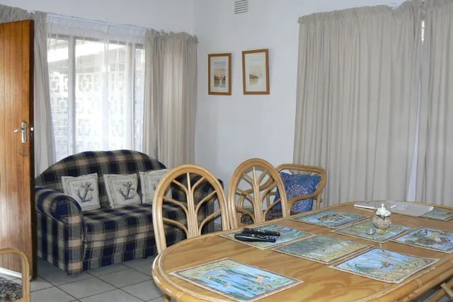 Open-plan living and dining area with a plaid sofa and wooden dining table
