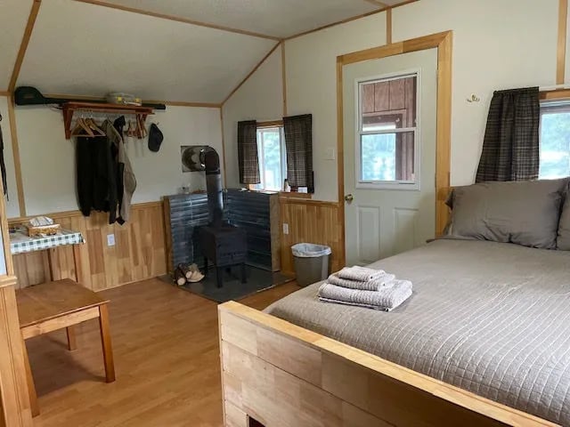 Cozy cabin interior with a queen bed, wood stove, and wood paneling