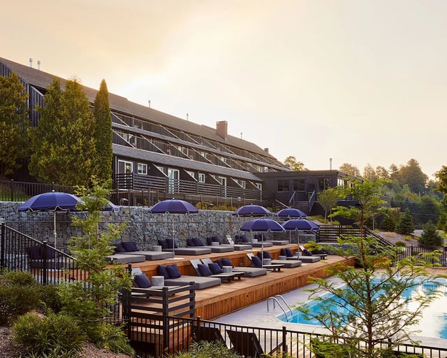 Group doing outdoor yoga on a patio with a dark modern building and green trees in the background.