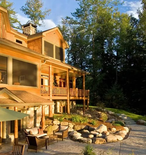 Rustic lodge building on a wooded hillside with lush green landscaping.