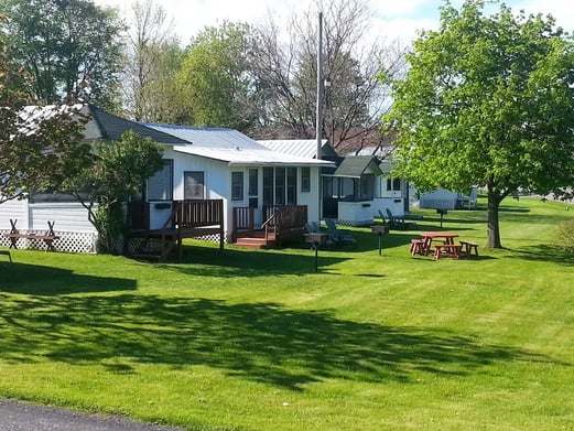 Close-up of the 'OFFICE' cabin exterior with hanging flower baskets and a screened porch