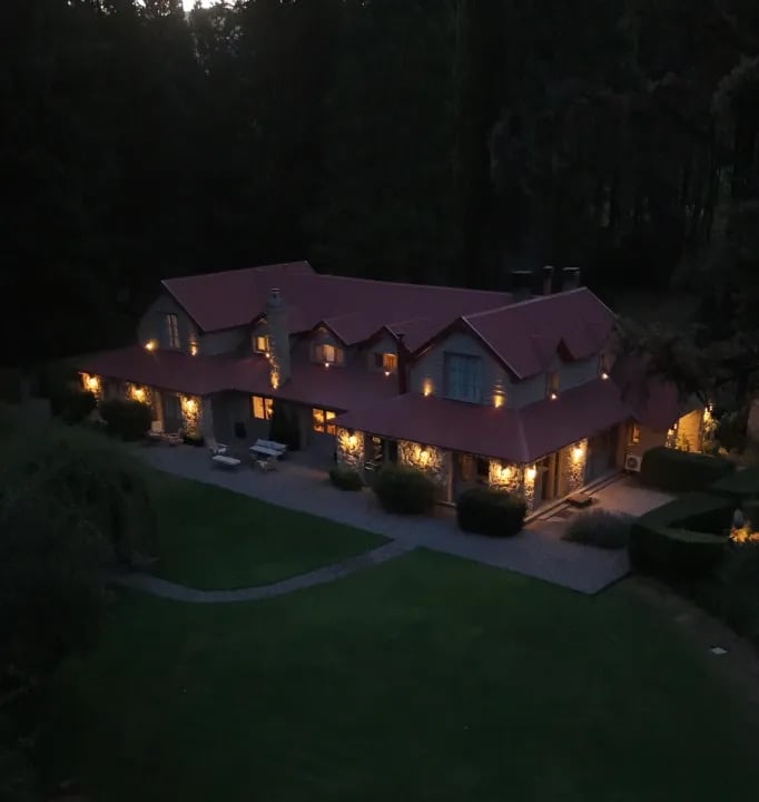 Aerial view of the lodge building illuminated at dusk, surrounded by dark trees