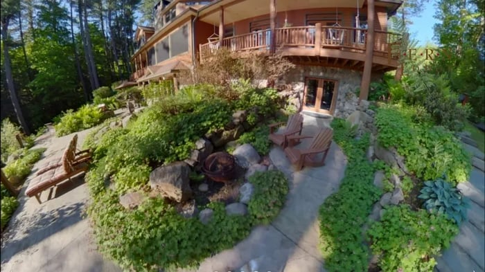 Side view of the lodge with multiple balconies and a stone patio with seating.