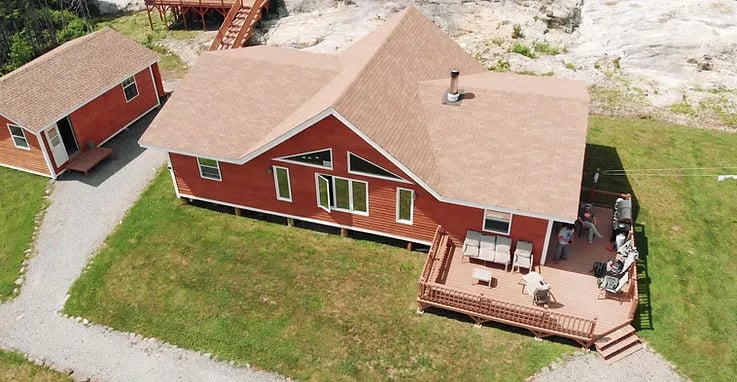 Aerial view of the main lodge and a smaller cabin with a gravel path.