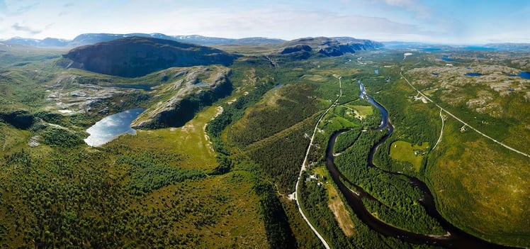 High aerial view of a winding river through a green, forested landscape with roads