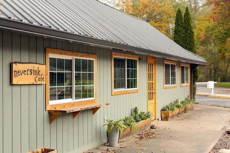 Exterior of a light green building with a metal roof and 'Neversink Cafe' sign