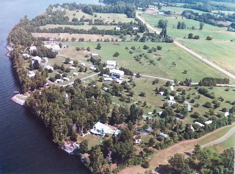 Aerial view of Champlain Resort Campground peninsula with lake, fields, and scattered buildings.