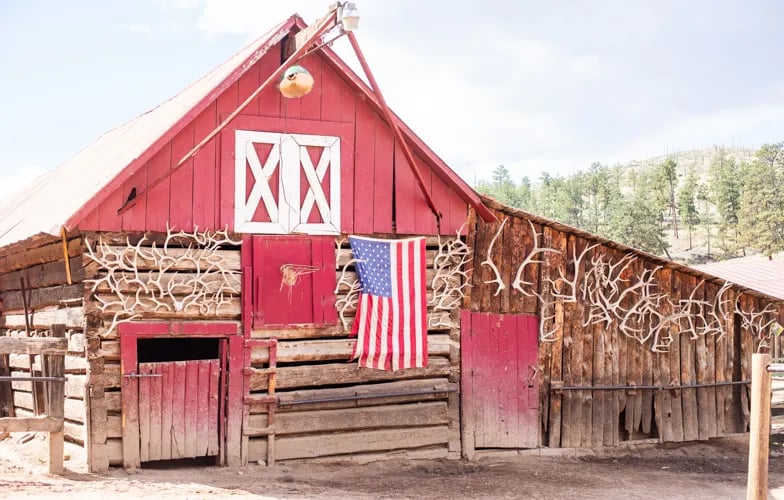 Red barn with white double doors and an American flag hanging on the side
