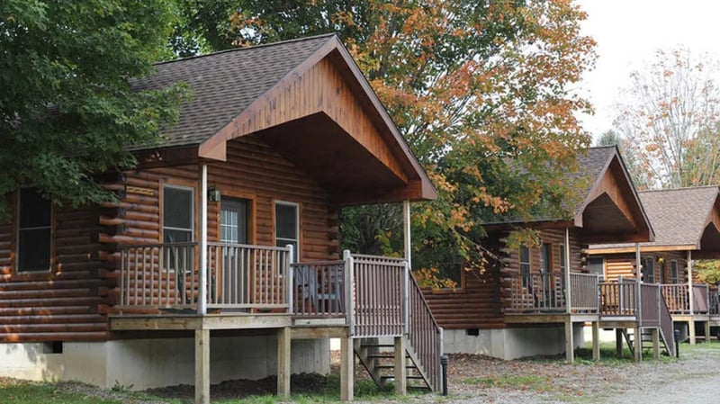 White multi-story lodge building with a green sign for West Branch Angler & Resort