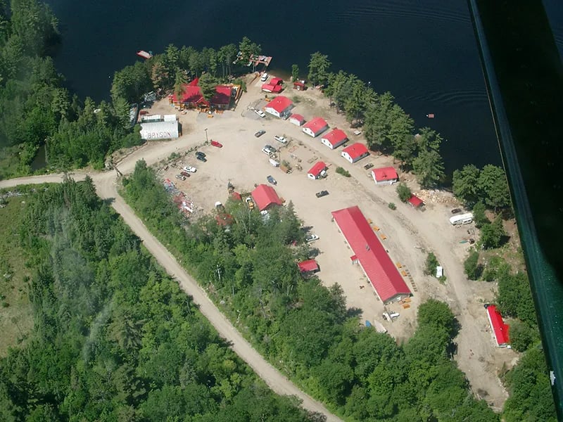 Aerial view of the lodge property with multiple cabins and a main building by the lake