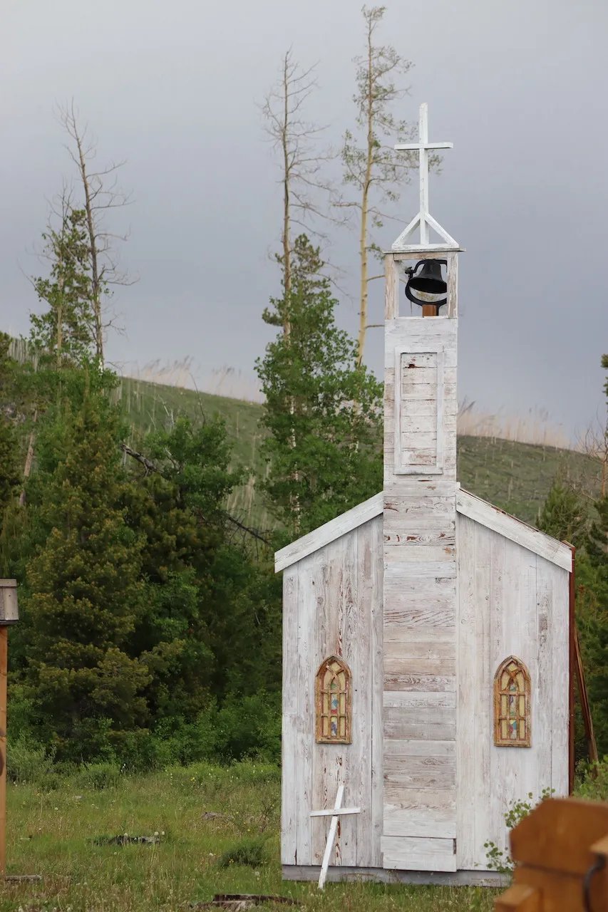 Small white chapel with a bell tower and cross in a green field
