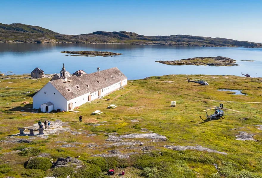 Aerial view of the long white main lodge building by a calm bay with rocky islands