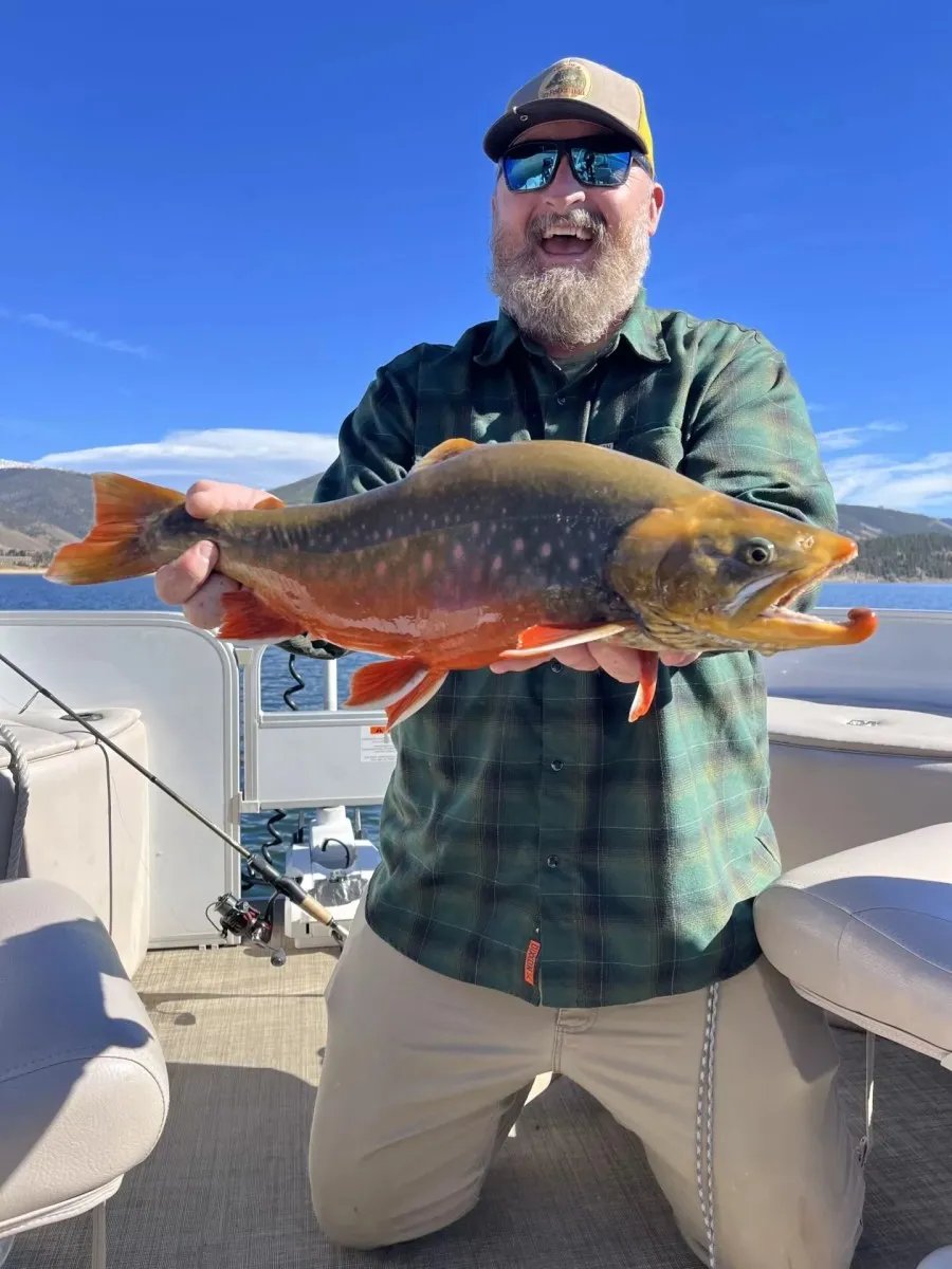 Bearded man holding a large spawning Arctic Char on a boat