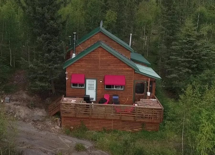 Deluxe Executive Cabin exterior with red awnings and a large wooden deck in a forest setting