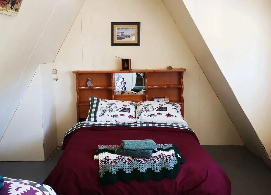 Cozy lodge room with a queen bed, sloped ceiling, and wooden headboard