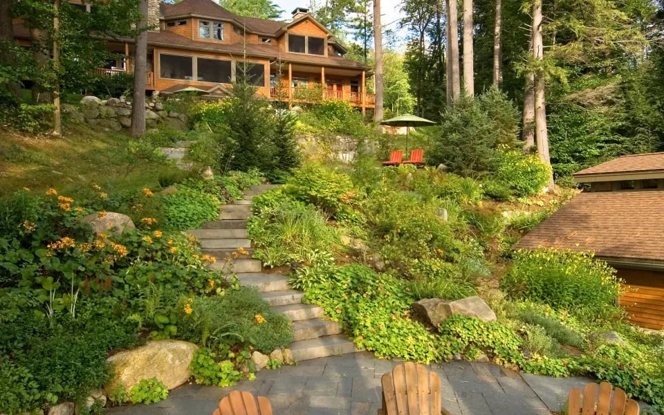 Stone walkway winding up a landscaped hillside towards the lodge, with Adirondack chairs in the foreground.